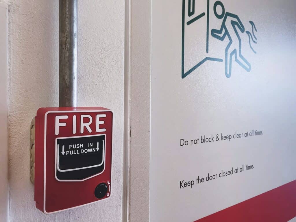 Close-up Red Fire Alarm Box Near Emergency Fire Exit Door