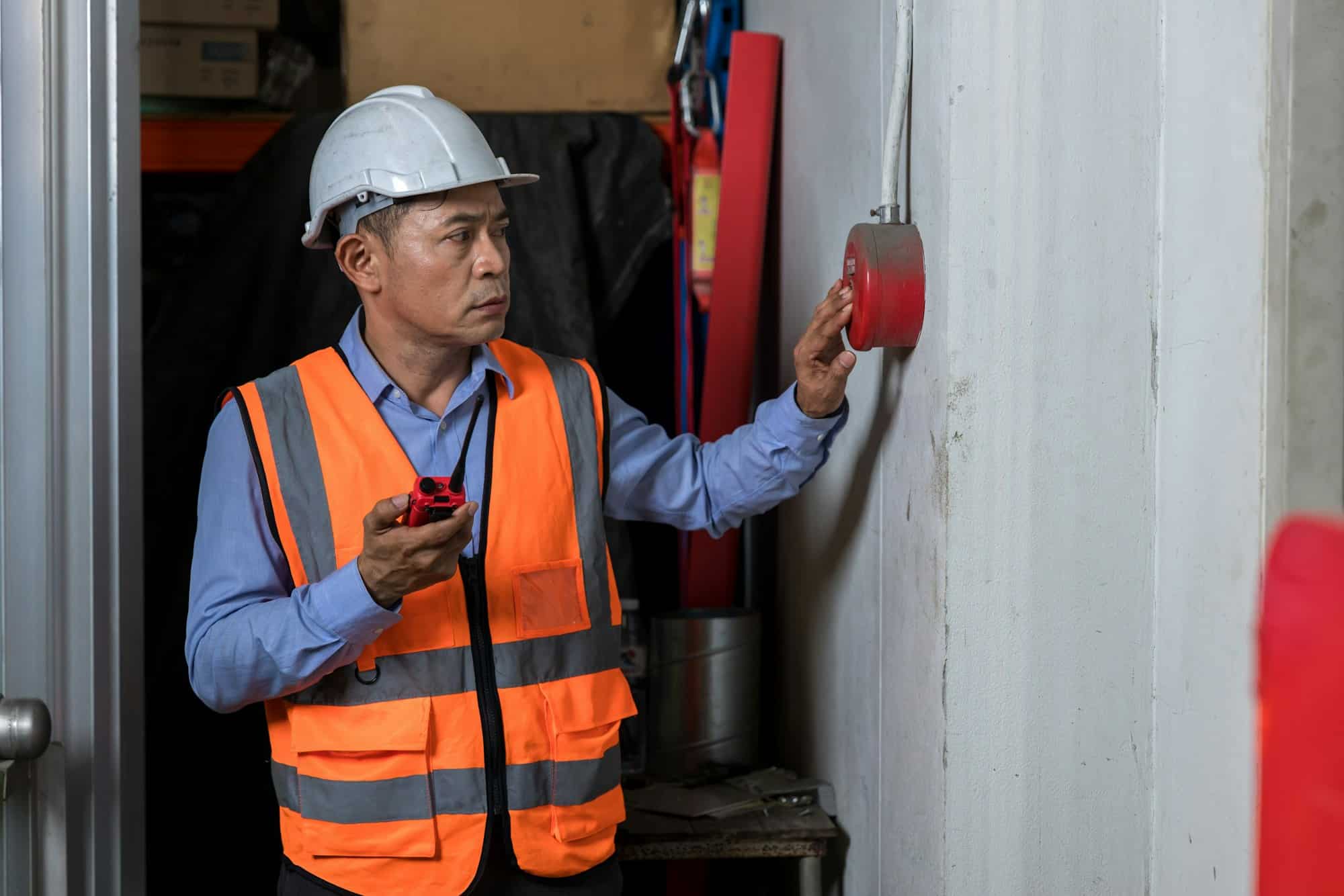 Foreman or worker pushing fire alarm on the wall. A fire! or Emergency case at the factory building.